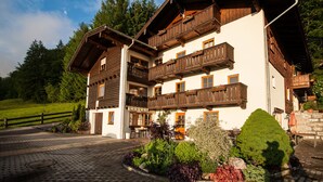Ein mehrstöckiges Chalet mit Holzbalkonen, einer Stein-Fassade und einer gepflasterten Auffahrt.