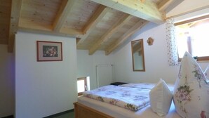 Une chambre avec un lit en bois, une fenêtre, un radiateur et un tableau encadré accroché au mur.