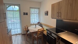 Une cuisine compacte avec des meubles en bois, une table à manger avec des chaises et un poêle noir.