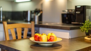 A modern kitchen with a wooden dining table, a plate of apples, and a potted plant. - Apartment Rauschberg 59 sqm, 1 sep. Bedroom, 1 living room, balcony, max. 2 pers (Ruhpolding)