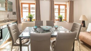Una cucina moderna con zona pranzo, caratterizzata da un tavolo in vetro, sedie e piante in vaso.