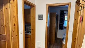 Een gang met houten deuren die leiden naar een keuken en een slaapkamer.