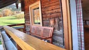 Eine Holzhütte mit einer Bank und einem Fenster mit Blick auf eine grüne Landschaft.