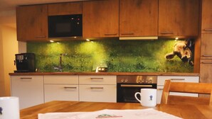 Eine Küche mit Holzausstattung, einer Mikrowelle, einer Kaffeemaschine und einer Wandverziierung.