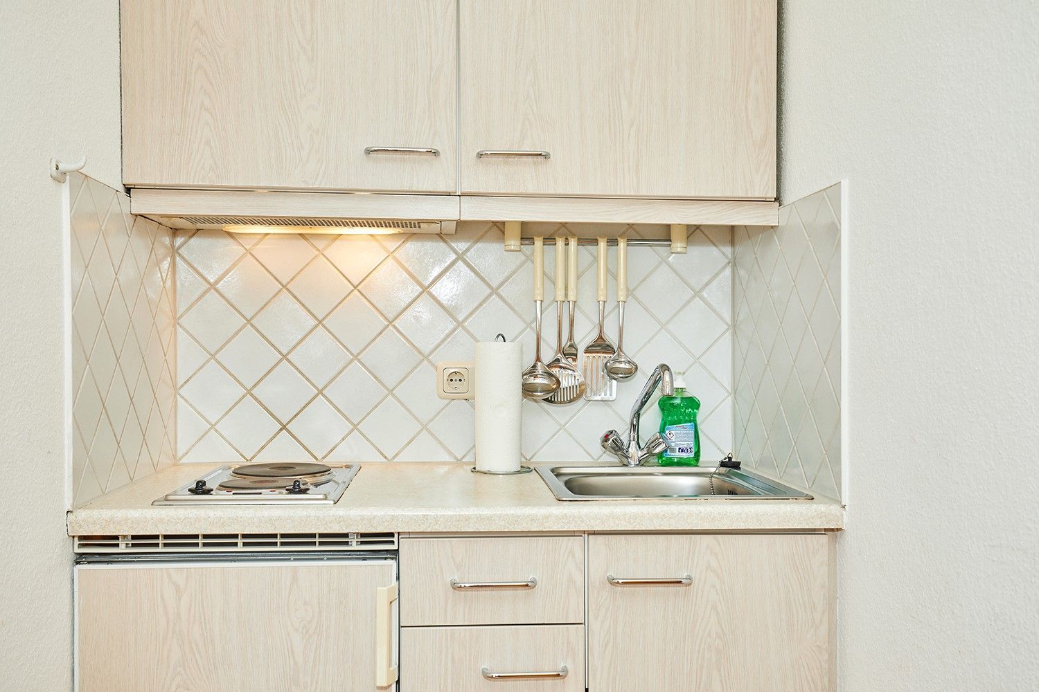 A kitchen with a sink, countertop, and wooden cabinets.