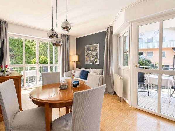 Una sala de estar moderna con comedor, ventanas amplias y vistas al exterior.