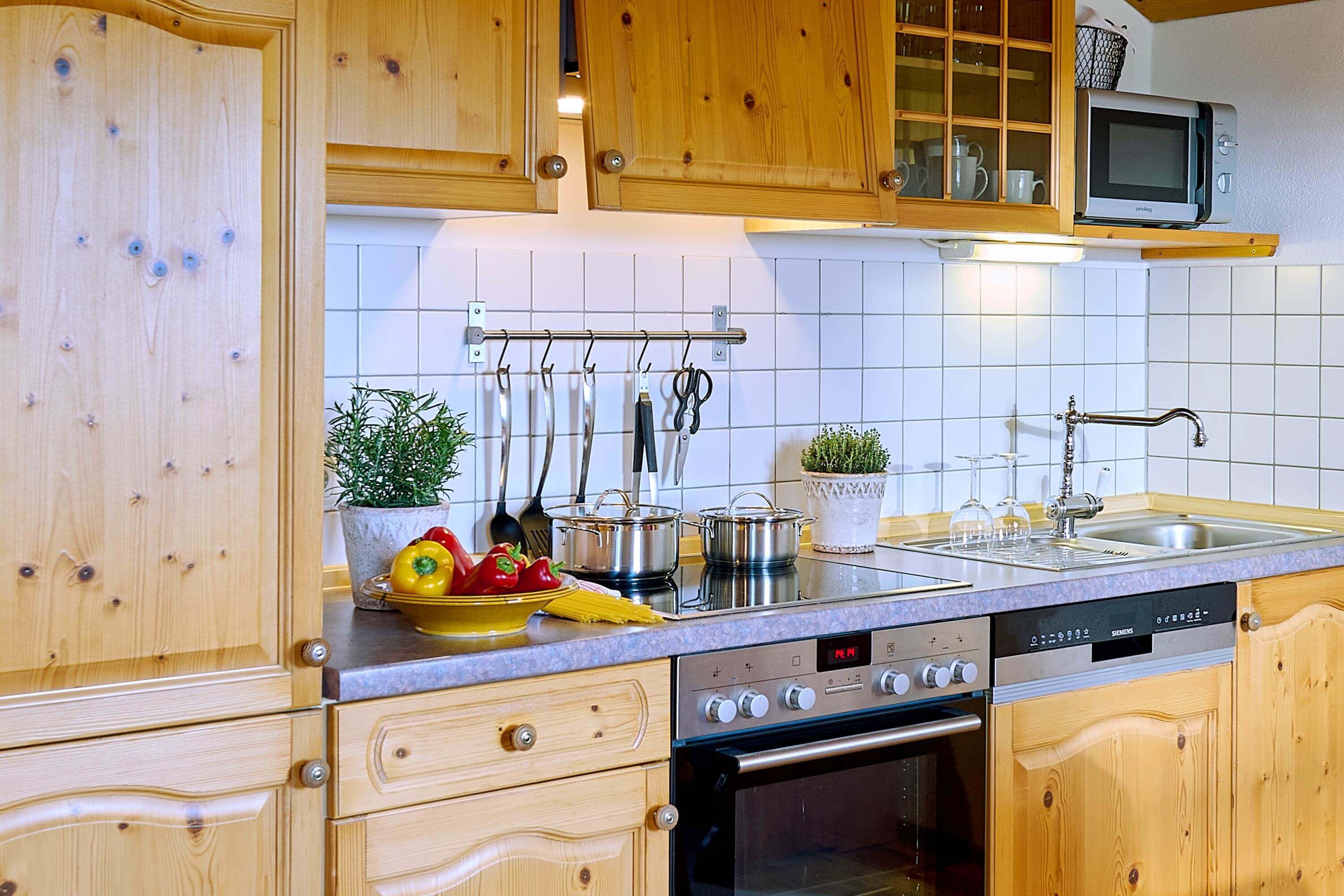 Une cuisine dotée de meubles en bois, d’un four à micro-ondes, d’une cuisinière et de divers ustensiles de cuisine.