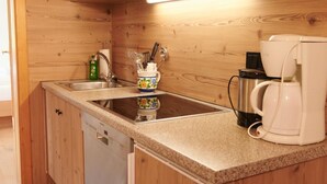 Una cucina con mobili in legno, un lavandino, una moka e una bottiglia di detersivo per piatti.