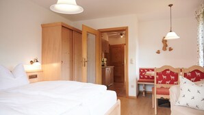 Una camera da letto con un letto grande, un'armadietto in legno e un angolo cottura sullo sfondo.