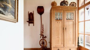 Un armadietto in legno con ante in vetro, una filatrice e un piccolo ripiano in legno con oggetti decorativi.