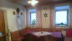 En mysig matplats med en träbänk som sittplats, ett bord med en duk och en kristallkrona.