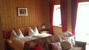 Ett rum med träpanel på väggarna, ett sängbord, en soffa och en säng.