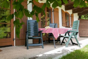 Un espace extérieur aménagé avec deux chaises et une table recouverte d’une nappe à carreaux.