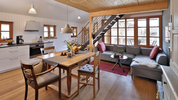 Eine moderne Küche mit Holzausstattung, einem Esstisch und einer Treppe, die zu einem Erkerraum führt.