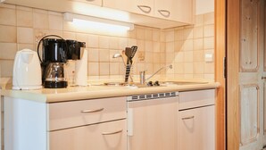 Une cuisine équipée d’une machine à café, d’une bouilloire et d’un grille-pain sur le plan de travail. On y trouve également des placards et un évier.