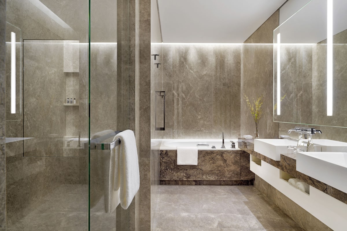 A modern bathroom with a glass shower enclosure, a marble vanity, and a large mirror.