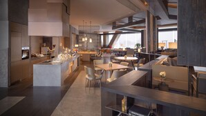 A modern restaurant with a central bar, multiple seating areas, and a high ceiling with exposed beams. - Grand Hyatt Xi An (Xi'an)