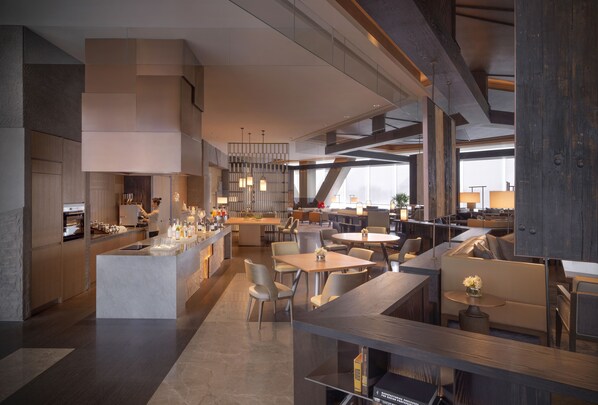 Un restaurante moderno con barra central, varias zonas de estar y un techo alto con vigas a la vista.