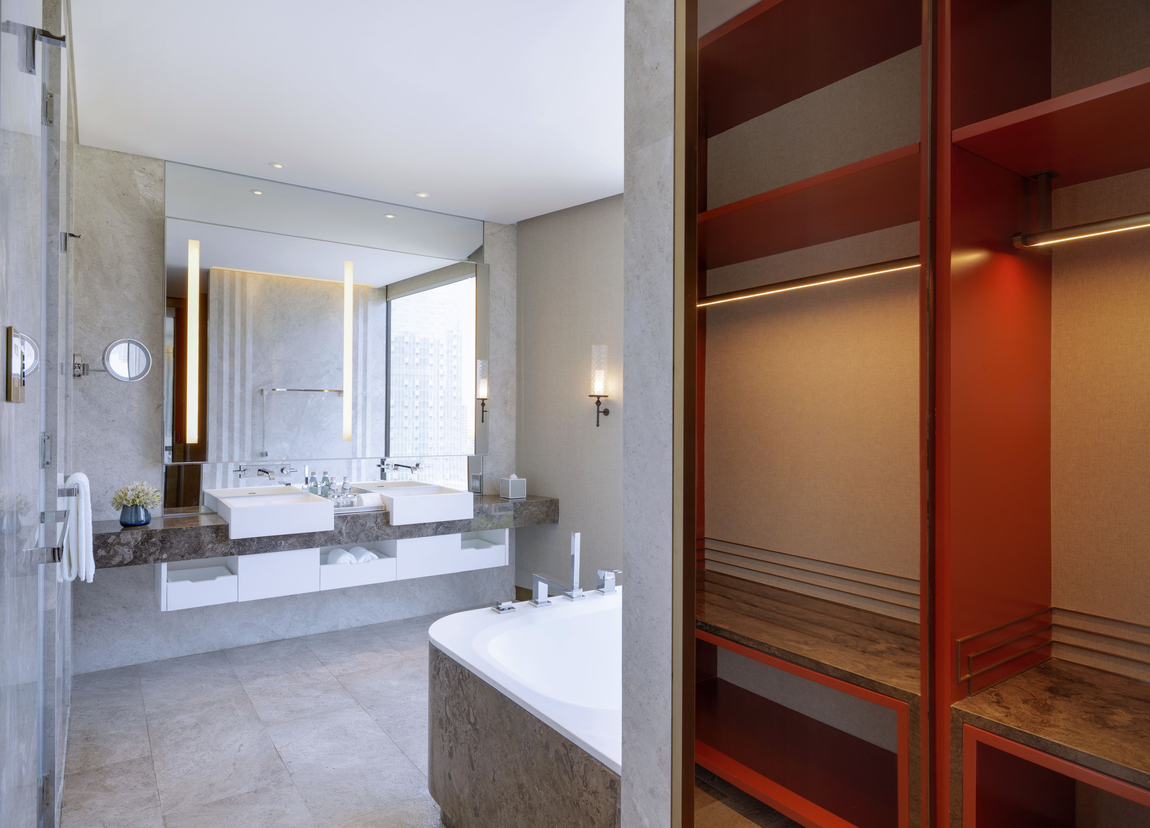 A modern bathroom with two sinks, a large mirror, and a bathtub.