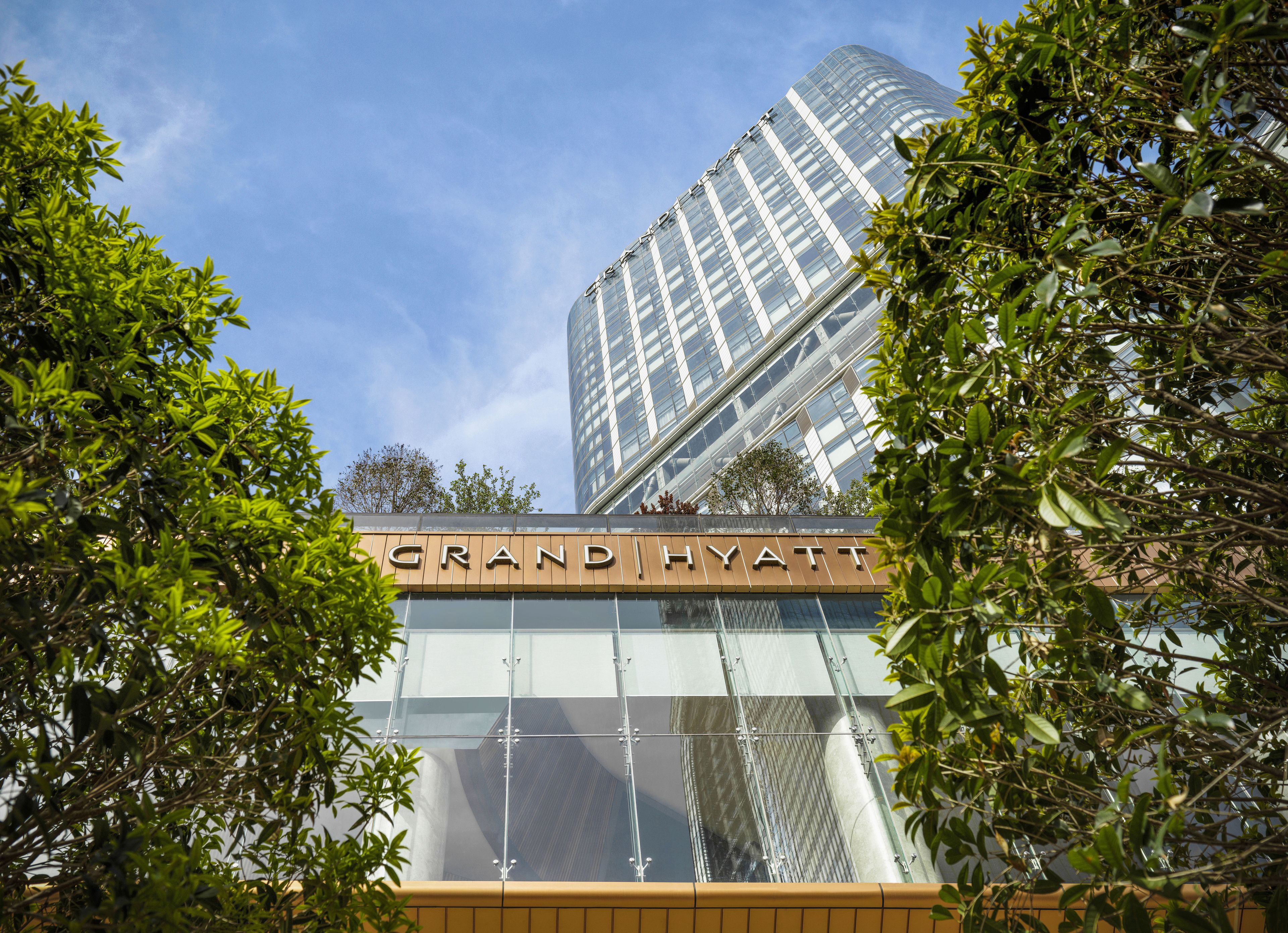 A Grand Hyatt hotel with a modern glass facade and a clear view of the sky.