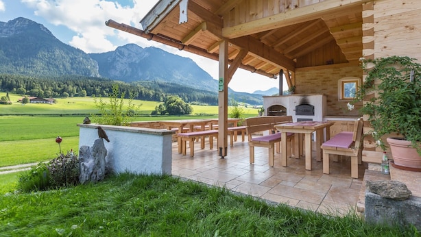 Eine Holzhütte mit Terrasse, Sitzgelegenheiten im Freien und Kamin.