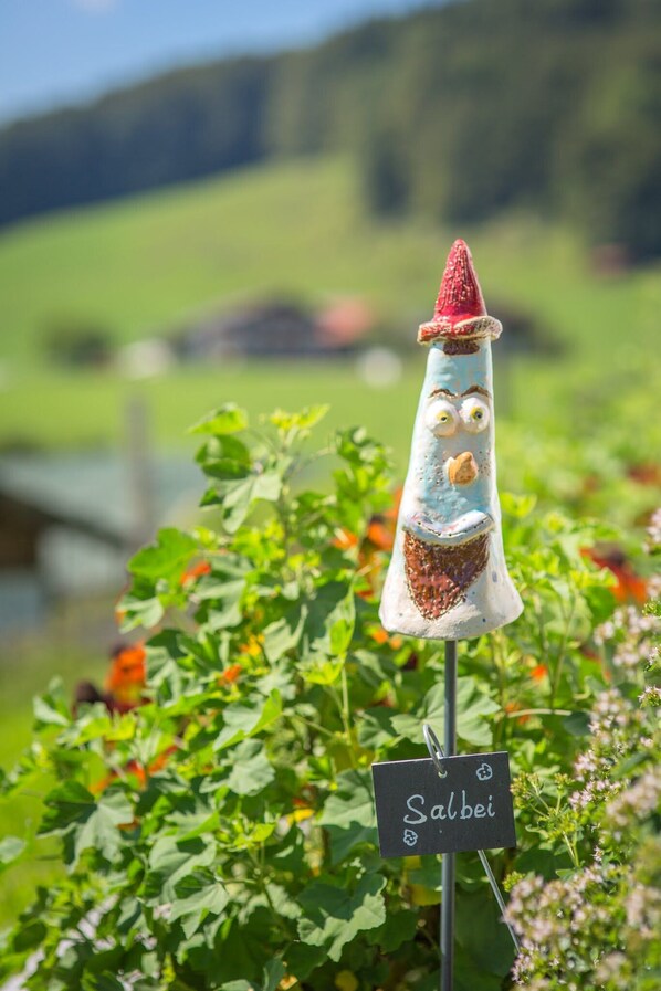 Un objet décoratif ressemblant à un saucisson, portant une étiquette indiquant « Salbei », dans un jardin.