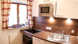 A compact kitchen with a microwave, stove, and sink.