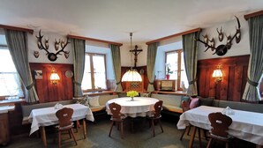 Een eetruimte met ronde tafels, houten stoelen en een kroonluchter in het midden.