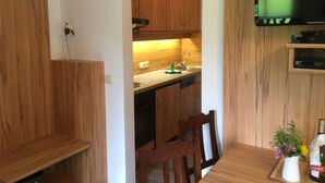 Una cocina moderna con armarios de madera, horno empotrado y comedor con mesa y sillas.