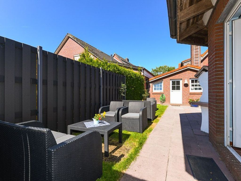 A patio with wicker furniture and a small table, a brick building, and a wooden fence.