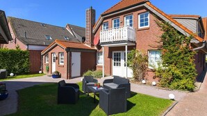 Et toetagers hus med en balkon, en velplejet græsplæne og udendørs møbler.