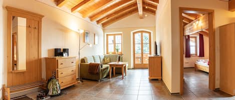 A cozy room with wooden beams, a sofa, a TV, and a bed.