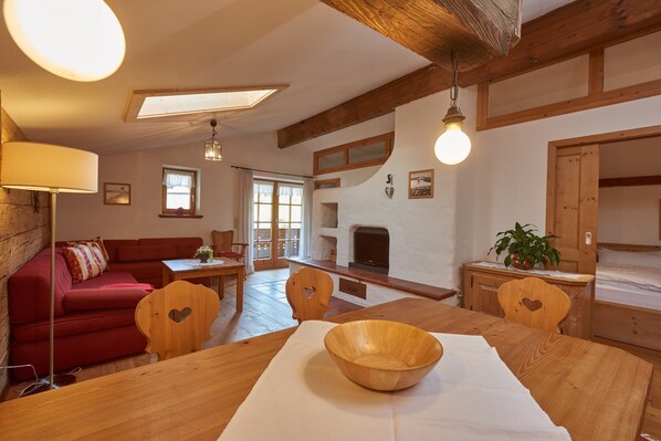 A cozy living room with a wooden dining table, red sofa, and a fireplace.