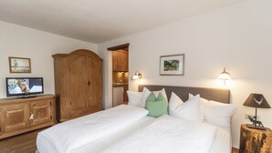 Ein Hotelzimmer mit einem großen Bett, einem Holfschrank, einem Fernseher und Wandleuchten.