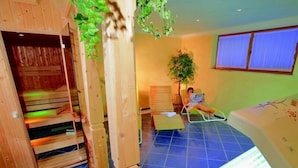 A sauna room with wooden benches, a massage table, and a large plant. - Ferienwohnung 4, 2 Personen, 50 qm., 1 Schlafzimmer, DU/WC, TV, Zimmersafe, Balkon (Oberwössen)