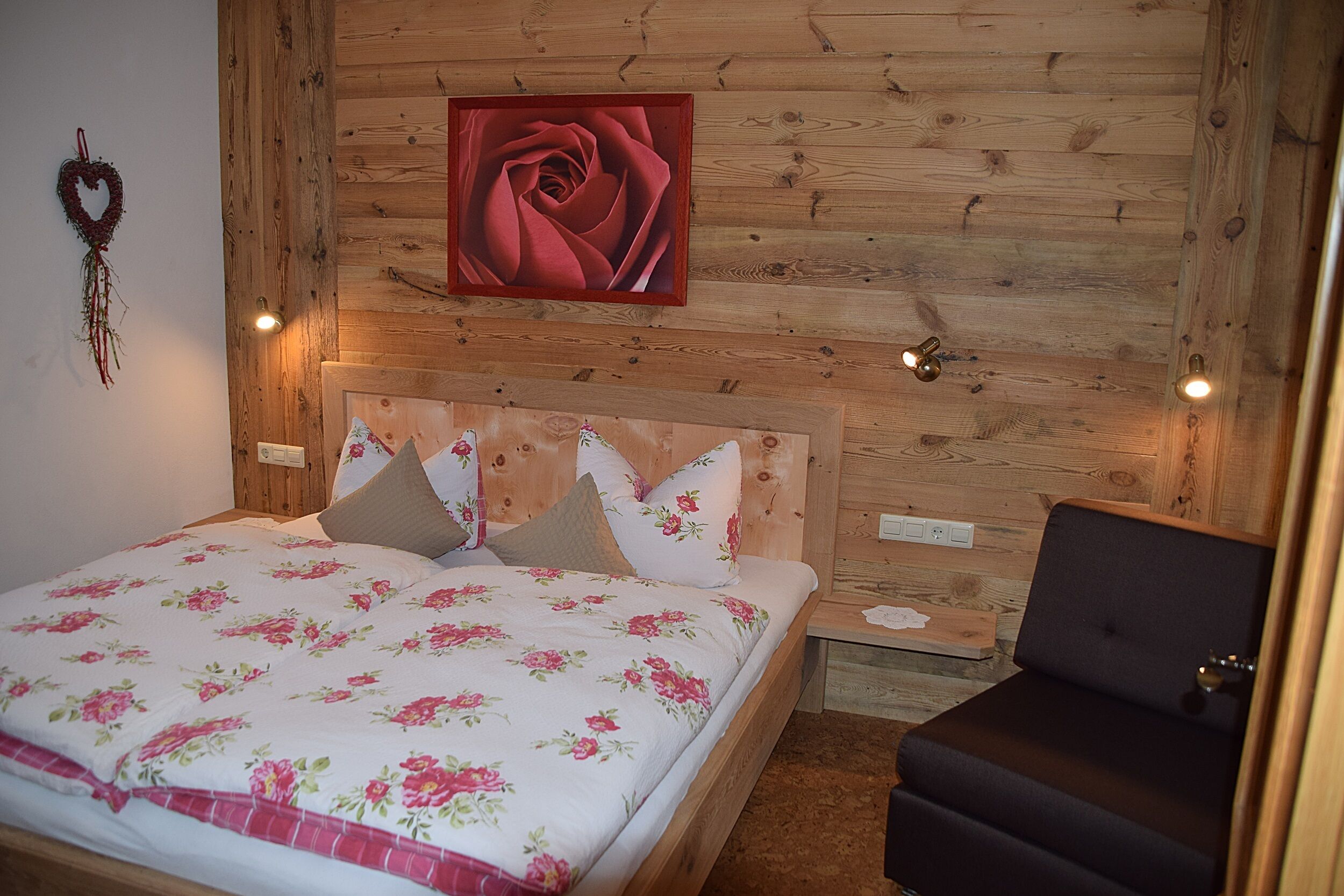 A wooden-paneled bedroom with a bed, pillows, a nightstand, and a chair.