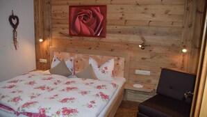 A wooden-paneled bedroom with a bed, pillows, a nightstand, and a chair. - Morgensonne one-room app. 28sqm, shower/WC, kitchenette, balcony (Reit im Winkl)