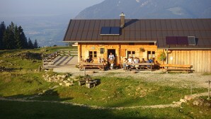 A wooden building with a sloped roof, solar panels, and a view of mountains. - Morgensonne one-room app. 28sqm, shower/WC, kitchenette, balcony (Reit im Winkl)