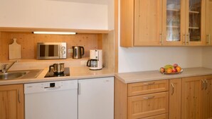 Uma cozinha compacta com armários de madeira, micro-ondas de aço inoxidável, cafeteira e lava-louças.