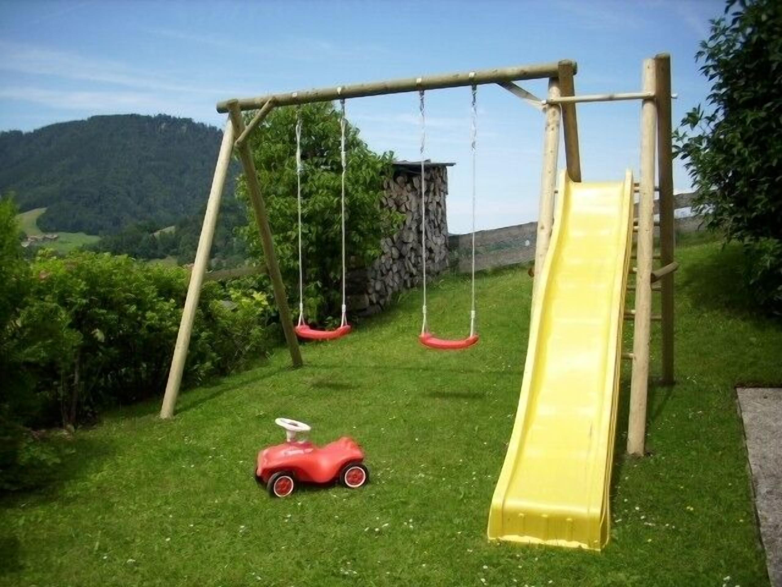 Un parque infantil con un tobogán amarillo y columpios.