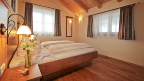 Une chambre à coucher avec un lit en bois, deux lampes de chevet, un miroir et un vase rempli de fleurs posé sur une table de chevet.
