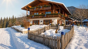 Eine Holzhütte mit Balkon, umgeben von Schnee und einem Holzzaun.