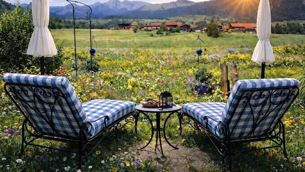 Ein Garten mit zwei gestreiften Liegestühlen, einem Tisch und Sonnenschirmen.