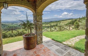 A stone archway with a potted tree, a wooden fence, and a view of a green landscape with hills. - Cozy home in Bibbiena AR with private swimming pool, can be inside or outside (Bibbiena AR)