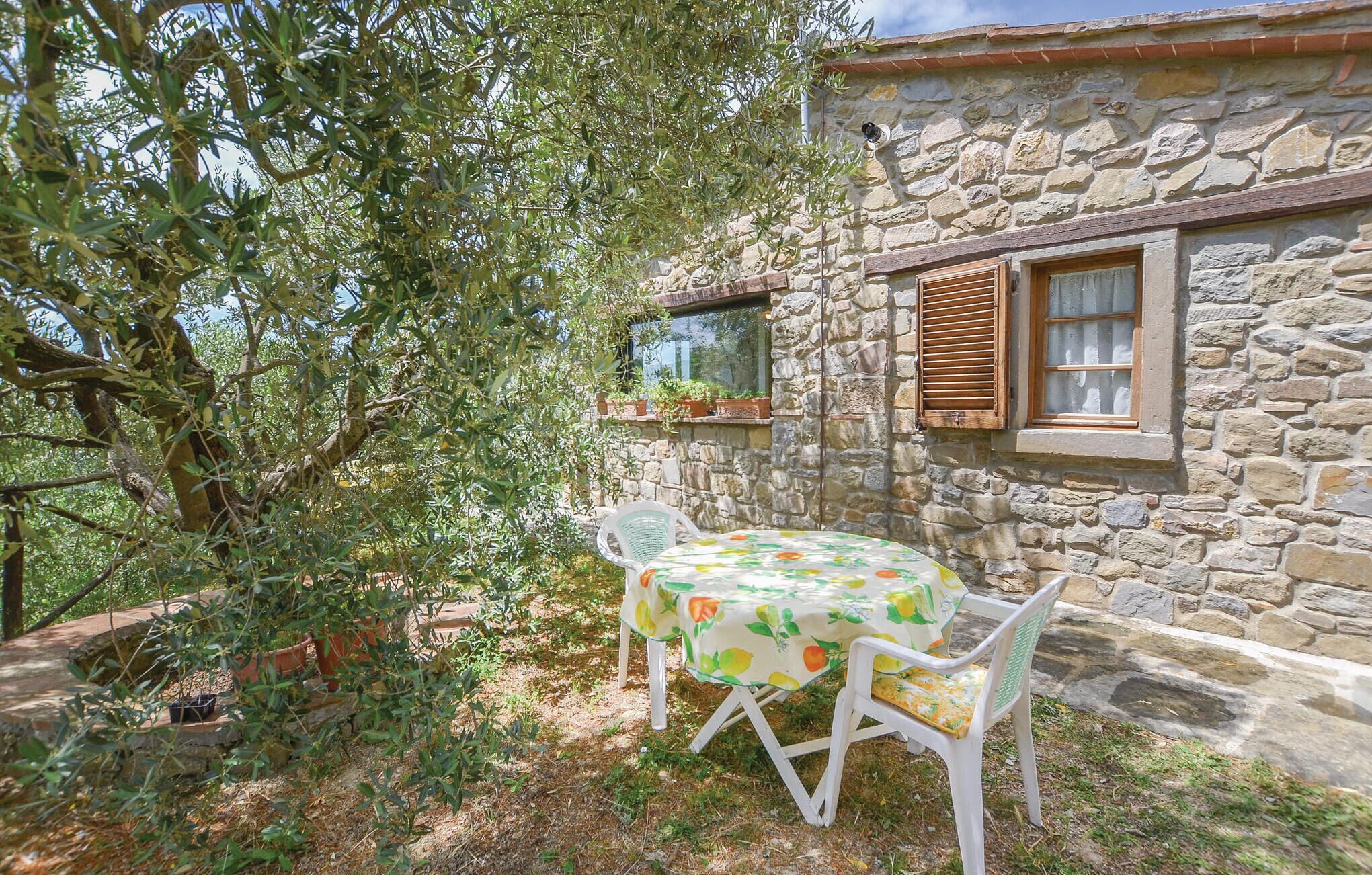 A stone building with a window and a table with chairs outside.