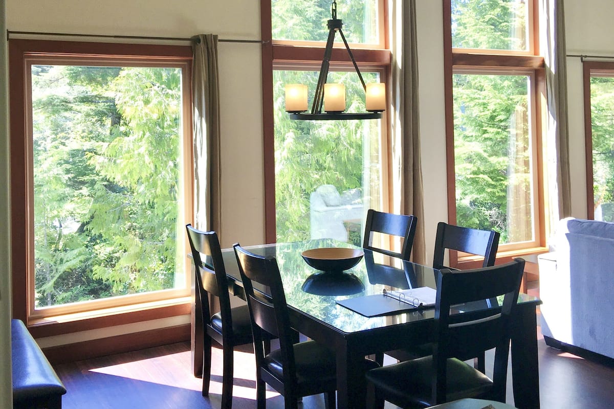 Uma área de refeições com mesa, cadeiras e um lustre.
