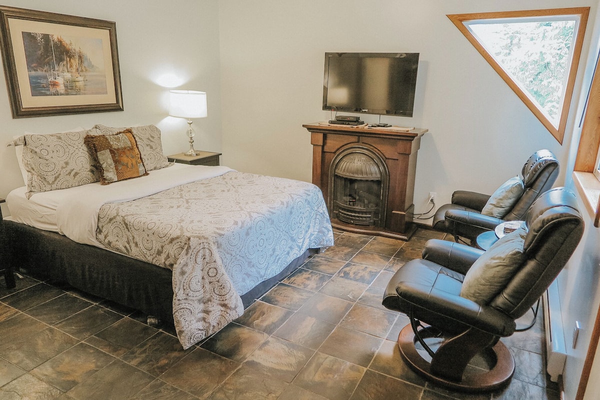 Quarto com cama, lareira, televisão e poltrona reclinável.
