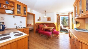 A cozy kitchen with wooden cabinets, a dining area with a bench, and a view of the outdoors.