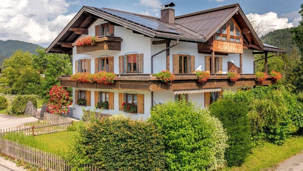 A two-story chalet with wooden balconies, a sloped roof, and a chimney.