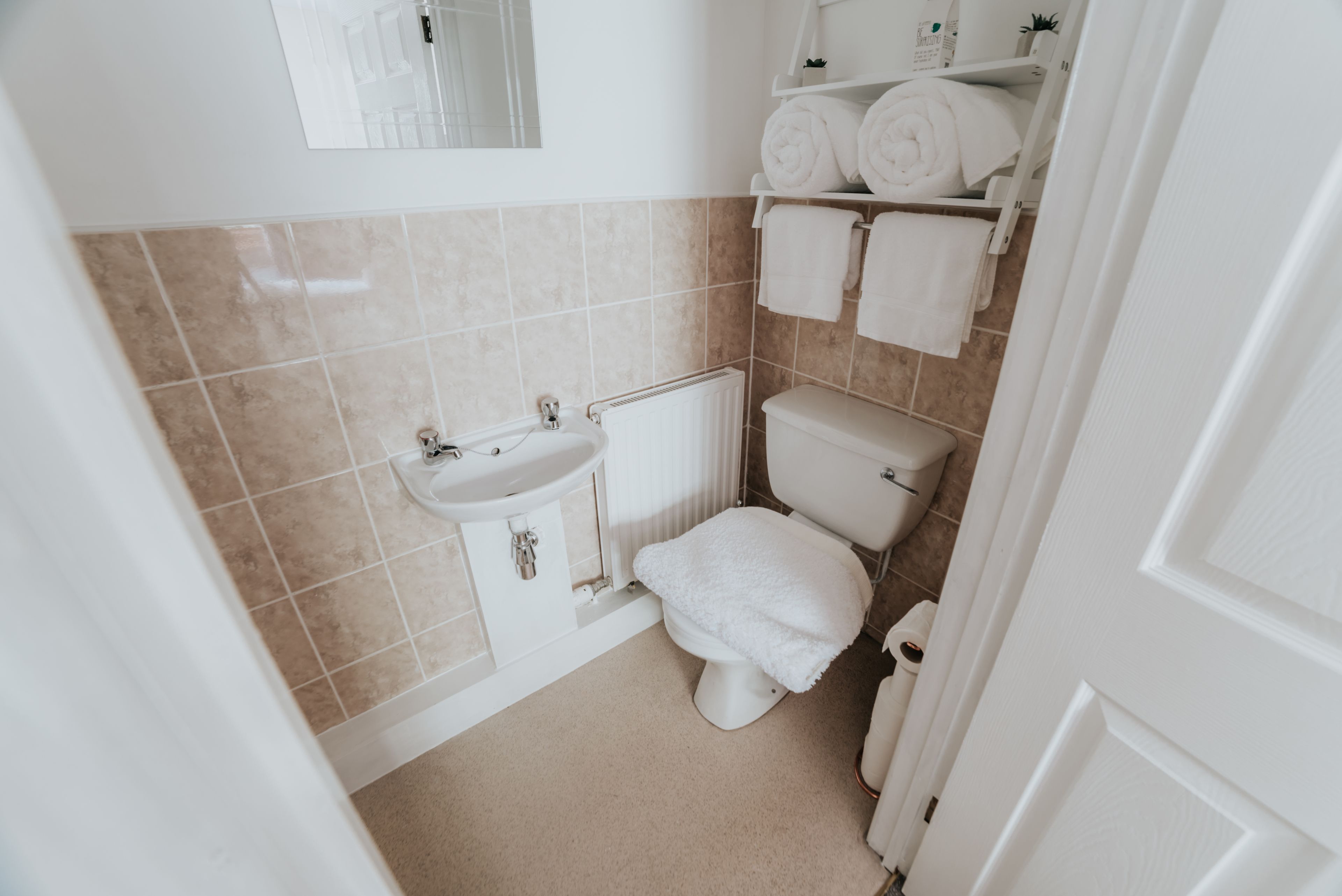 A small, clean bathroom with a toilet, sink, and towel rack.